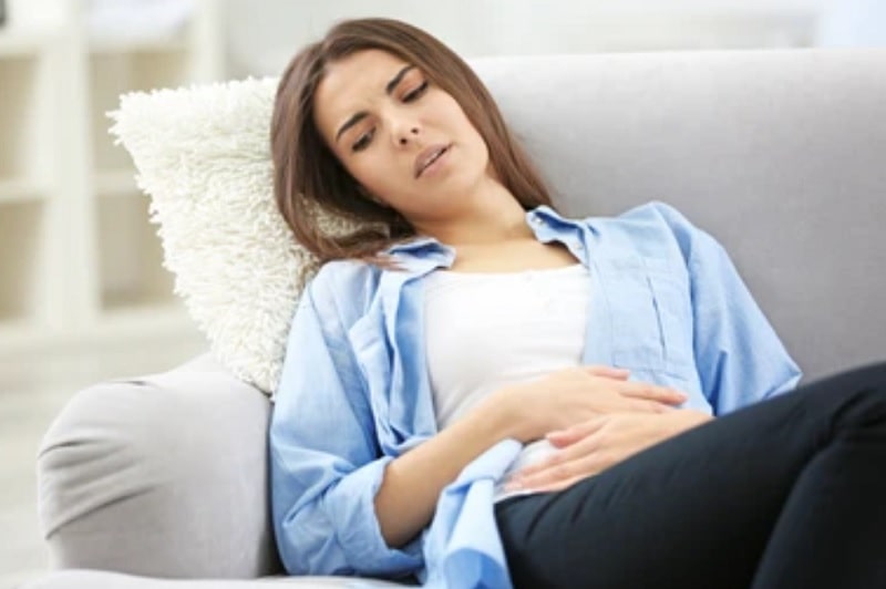 Ovulation Symptoms Woman Lying down holding her stomach